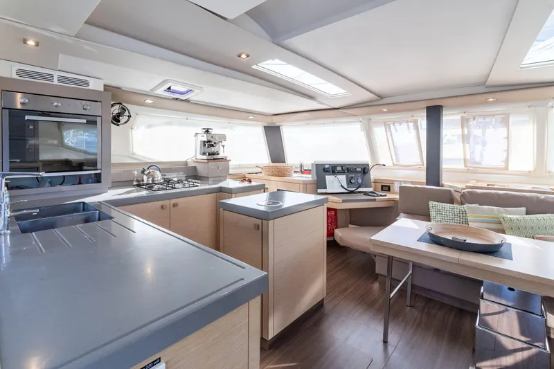 Grand Crew Yacht Photos Pics Luxurious interior of 2019 Fountaine Pajot 47 catamaran with modern kitchen and seating area.