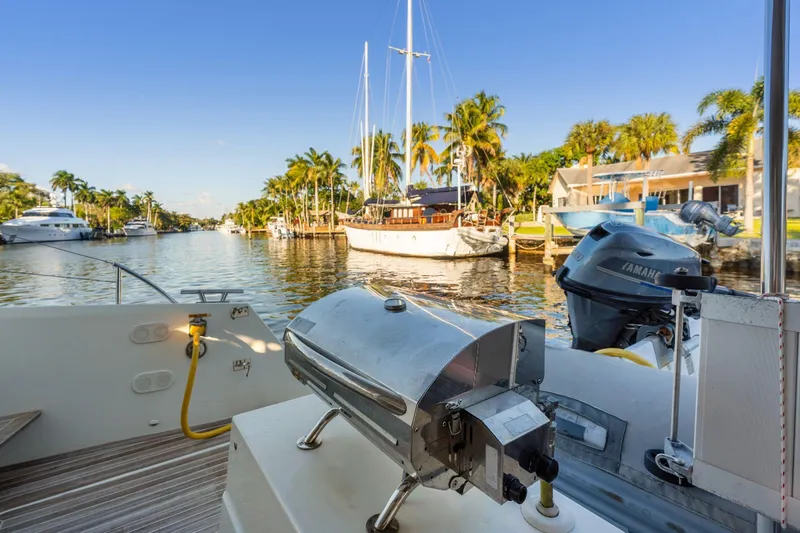 Grand Crew Yacht Photos Pics 2019 Fountaine Pajot 47 yacht with grill, docked in a scenic canal with palm trees.