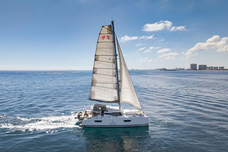Grand Crew Yacht Photos Pics 2019 Fountaine Pajot 47 catamaran sailing on calm ocean waters under a clear blue sky.