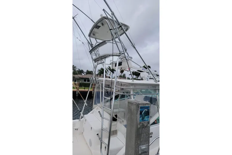 Miss Jayla Yacht Photos Pics 2004 Cabo 40 Express boat with tower, docked near waterfront homes.