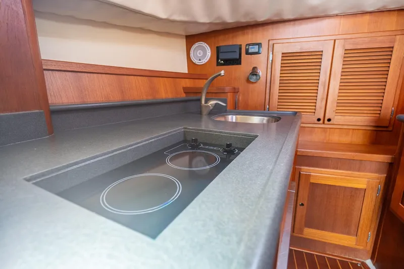Volatility Yacht Photos Pics Luxurious 2003 San Juan SJ 38 yacht kitchen with modern stovetop and wooden cabinetry.