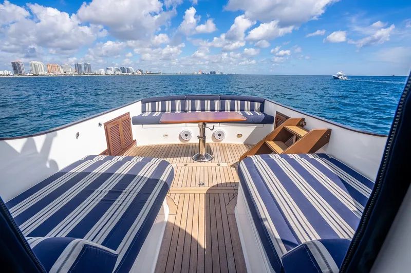 Volatility Yacht Photos Pics Luxury San Juan SJ 38 yacht deck with striped seating, ocean view, and city skyline.