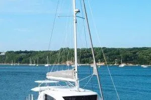 Isola Yacht Photos Pics 2018 Leopard 40 catamaran sailing on a serene blue lake with forested shoreline.