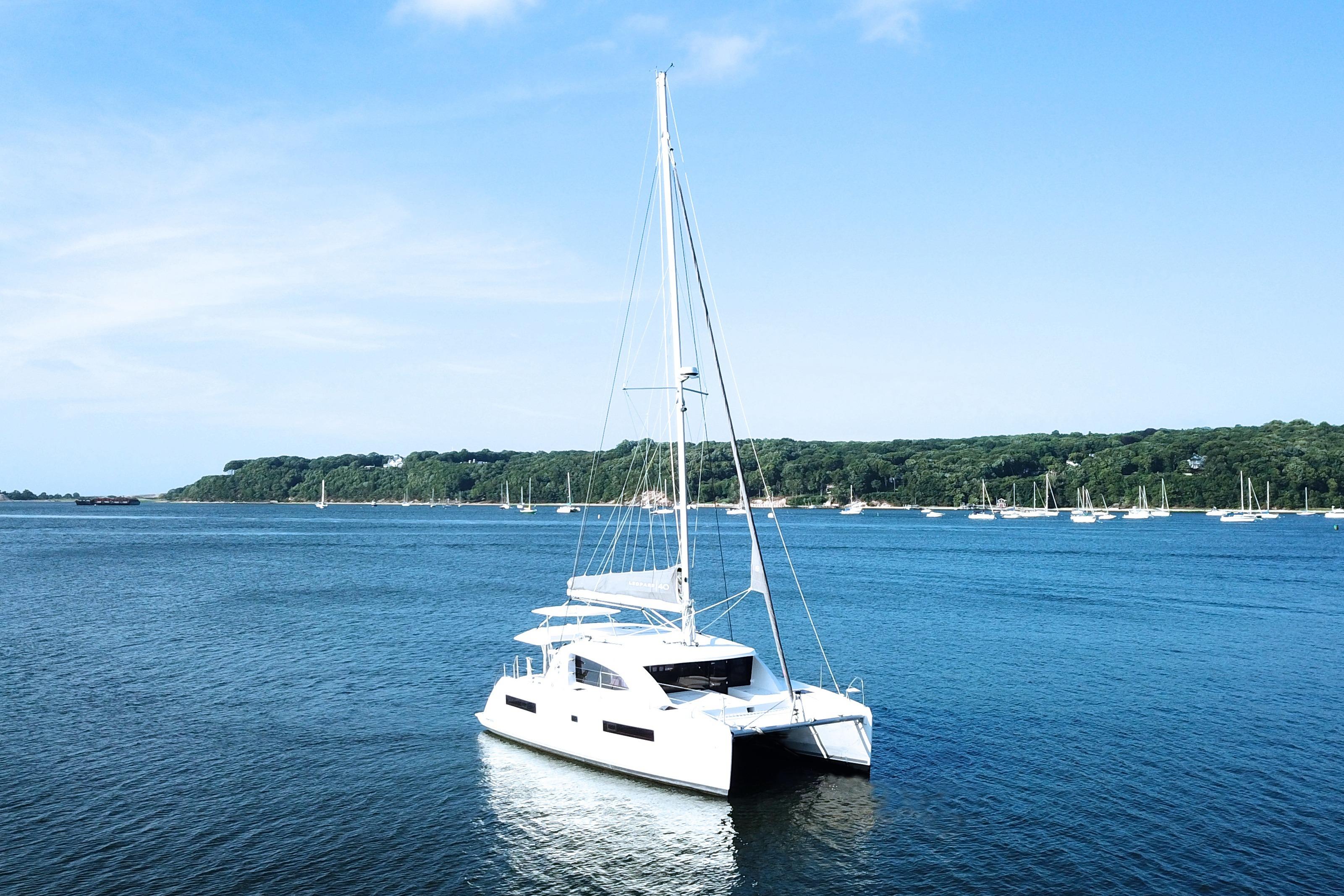 2018 Leopard 40 catamaran sailing on a serene blue sea with lush green shoreline.