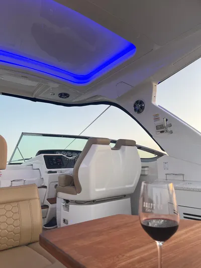 Lady Faby Yacht Photos Pics Interior of 2019 Sea Ray Sundancer 350 yacht with blue LED lighting and wine glass on table.