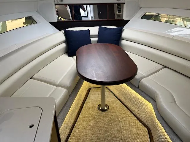  Yacht Photos Pics 2022 Monterey 295 Sport Yacht interior with white seating, wooden table, and ambient lighting.