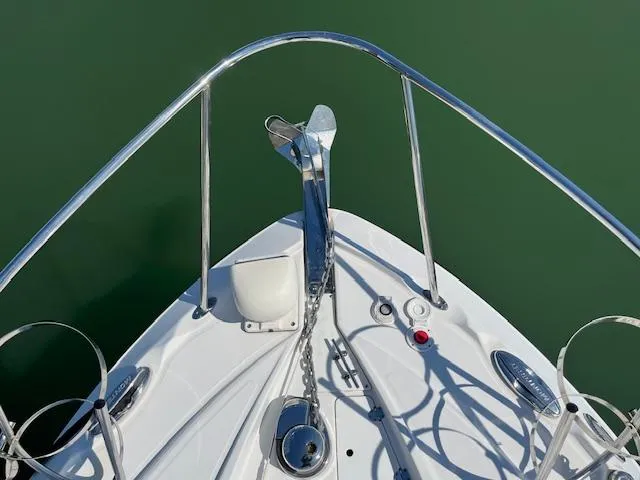  Yacht Photos Pics Bow of 2022 Monterey 295 Sport Yacht with anchor and railing, on calm green water.