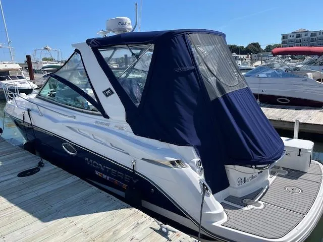  Yacht Photos Pics 2022 Monterey 295 Sport Yacht docked, featuring a sleek design and navy blue canopy.
