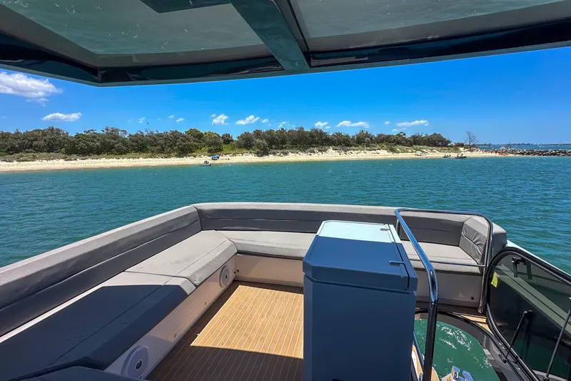 Da Mare Yacht Photos Pics 2023 OKEAN 52 yacht with spacious deck, overlooking serene coastal waters and sandy beach.