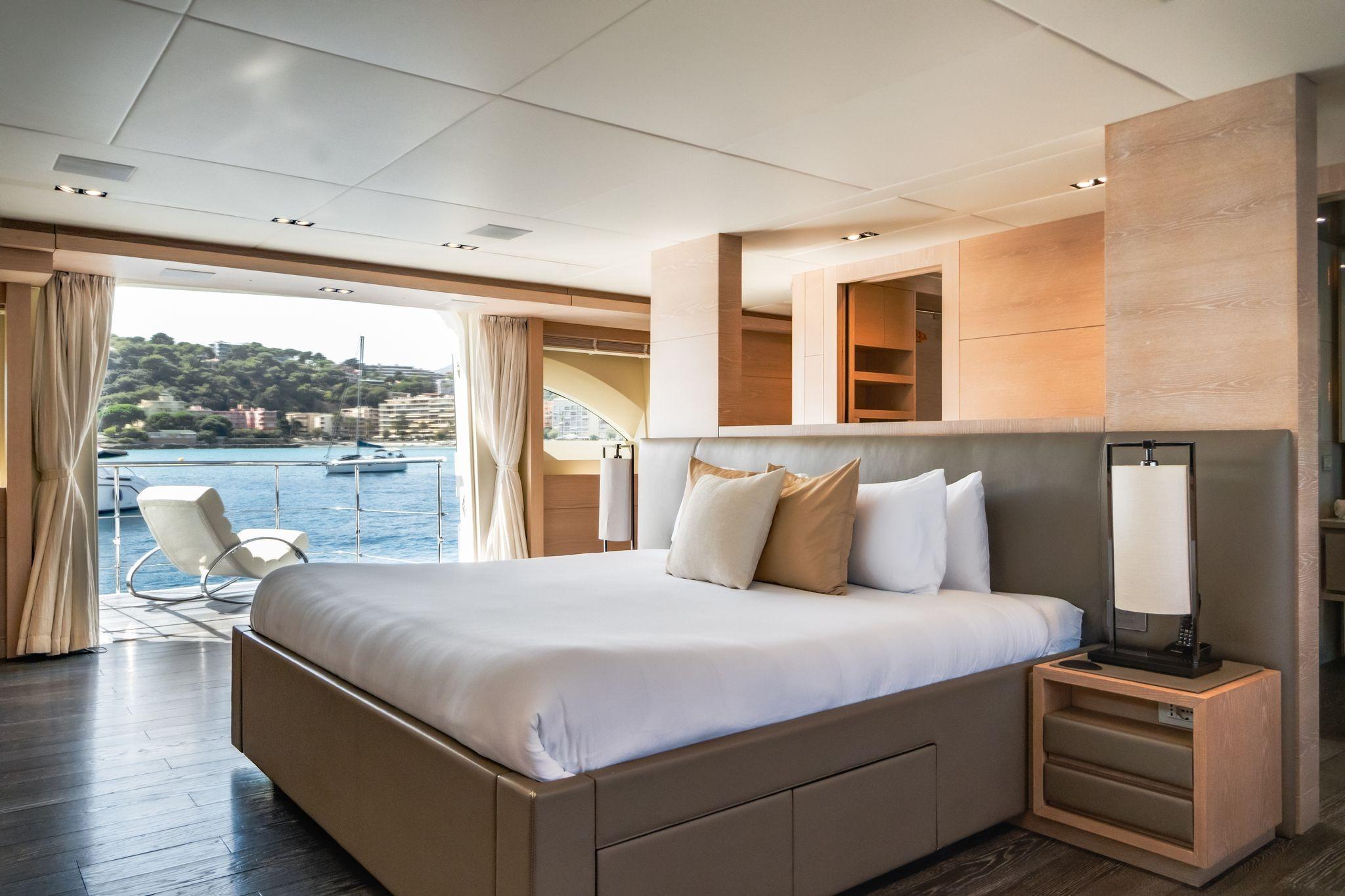 Luxurious yacht bedroom with waterfront view, featuring modern decor and elegant furnishings.