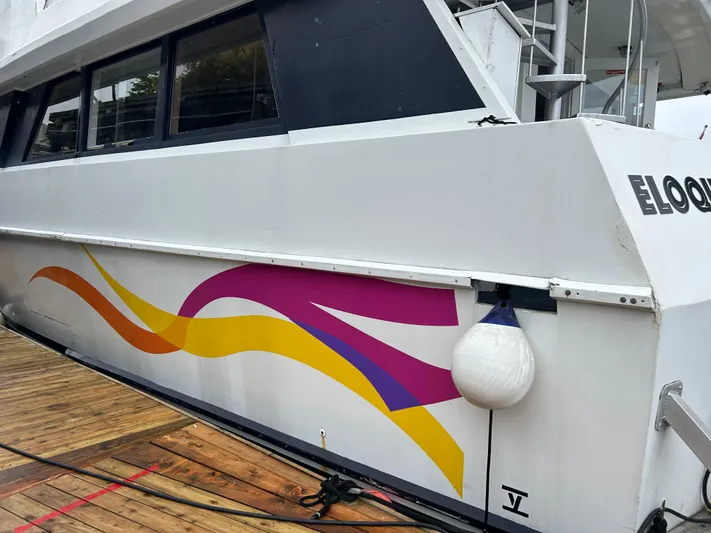 Eloquent Yacht Photos Pics Palmer Marine 70 Pilothouse 1990 with colorful wave design docked at marina.