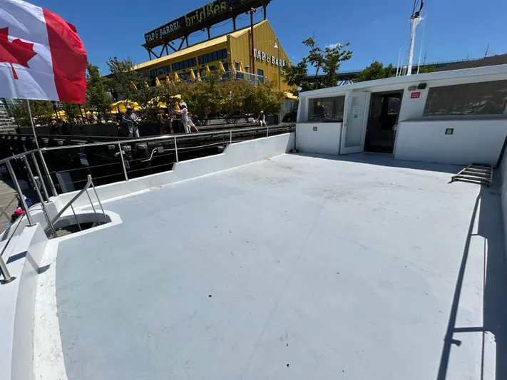 Eloquent Yacht Photos Pics Open deck of 1990 Palmer Marine 70 Pilothouse with Canadian flag, docked near a yellow building.