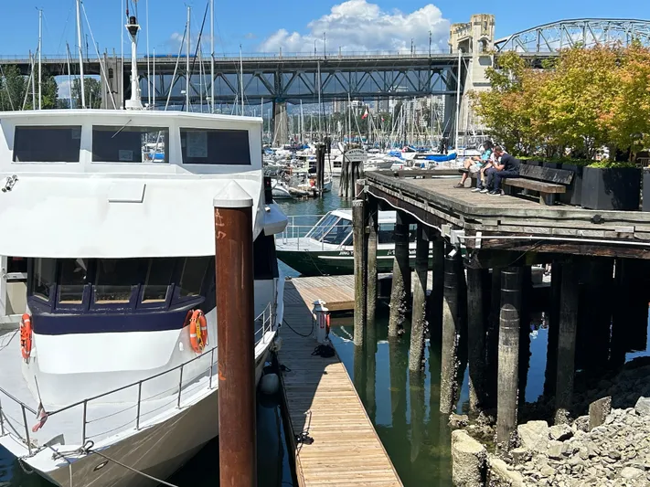 Eloquent Yacht Photos Pics Palmer Marine 70 Pilothouse yacht docked near a wooden pier, with a bridge in the background.