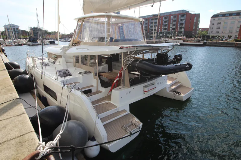 Vela Yacht Photos Pics 2021 Lagoon 46 catamaran docked in a marina, featuring spacious deck and modern design.