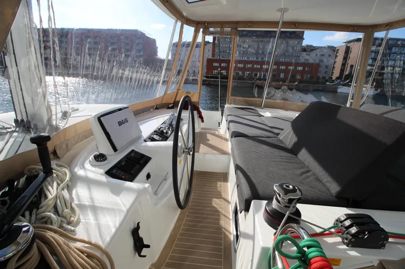 Vela Yacht Photos Pics 2021 Lagoon 46 yacht cockpit with steering wheel, ropes, and waterfront view.