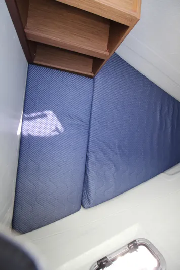 Vela Yacht Photos Pics Interior cabin of 2021 Lagoon 46 catamaran with blue mattress and wooden shelves.
