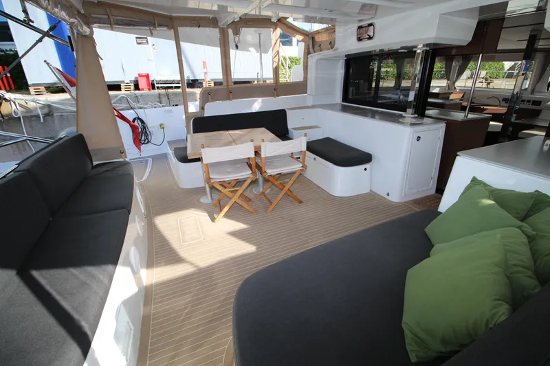 Vela Yacht Photos Pics Spacious Lagoon 46 catamaran interior with seating, table, and cushions, 2021 model.