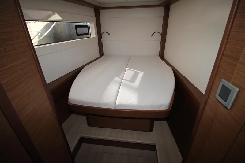 Vela Yacht Photos Pics Interior cabin of 2021 Lagoon 46 catamaran with a cozy bed and wooden finish.