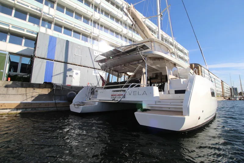 Vela Yacht Photos Pics 2021 Lagoon 46 catamaran docked at a marina, showcasing its sleek design and spacious deck.