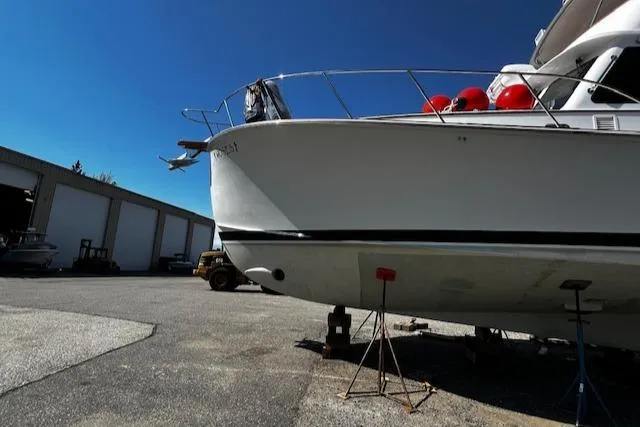 Moses Yacht Photos Pics 2003 Lyman-Morse Wesmac Sportfish Cruiser on stands in a boatyard under clear blue sky.