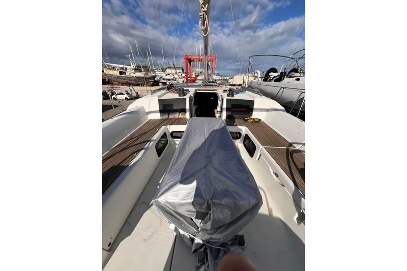 Cum Laude Yacht Photos Pics 2017 Dufour 512 Grand Large sailboat deck with covered equipment, docked under cloudy sky.