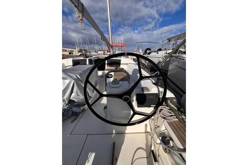 Cum Laude Yacht Photos Pics 2017 Dufour 512 Grand Large sailboat cockpit with steering wheel and marina view.