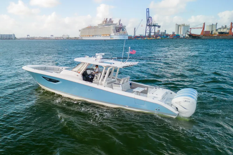  Yacht Photos Pics 2022 Pursuit S 428 Sport boat cruising near a busy port with a cruise ship.