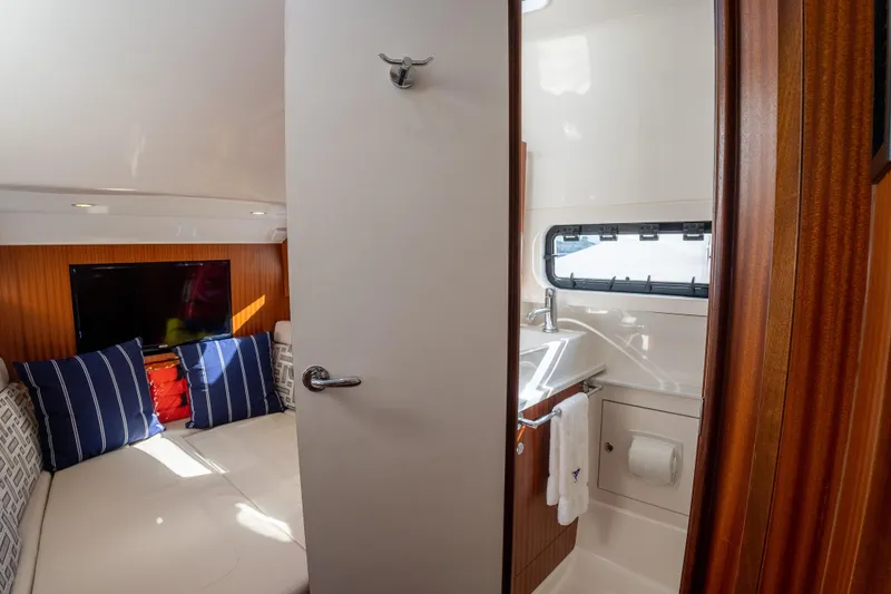  Yacht Photos Pics 2022 Pursuit S 428 Sport cabin interior with bed, pillows, and bathroom.