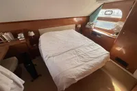 Cozy bedroom in 2008 Beneteau Swift Trawler 52 with wooden accents and natural light.
