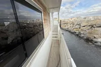 2008 Beneteau Swift Trawler 52 docked, showcasing side deck and scenic waterfront view.