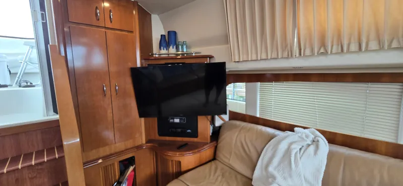 Live Now Yacht Photos Pics Interior of 2006 Carver 44CPMY yacht with TV, wooden cabinets, and beige sofa.