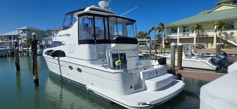 Live Now Yacht Photos Pics 2006 Carver 44CPMY yacht docked at marina, clear blue sky, waterfront homes in background.