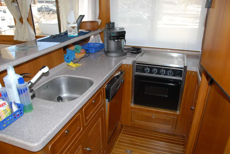  Yacht Photos Pics Compact kitchen in 2026 Selene 54 yacht with sink, stove, and wooden cabinetry.