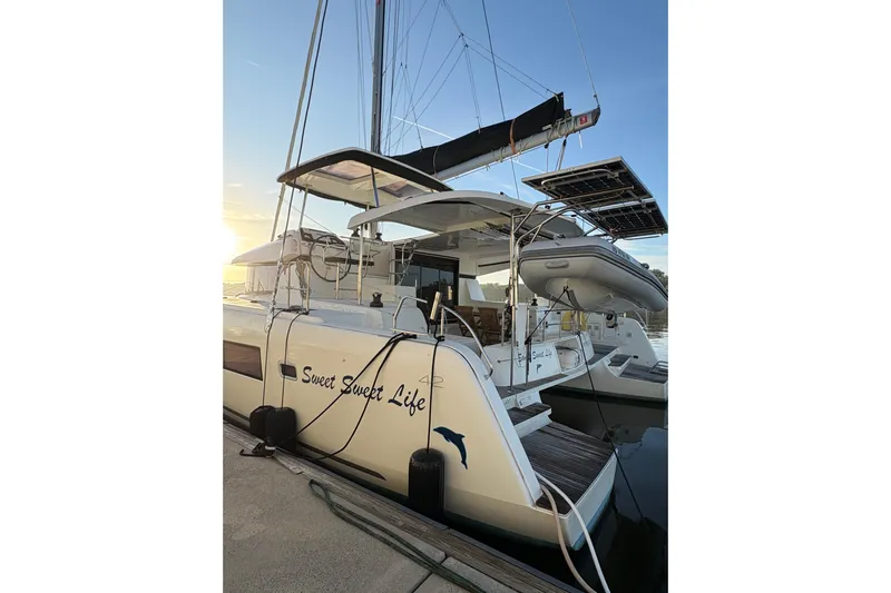 Sweet Sweet Life Yacht Photos Pics 2020 Lagoon 42 catamaran docked at sunset, featuring solar panels and an inflatable boat.