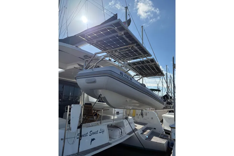 Sweet Sweet Life Yacht Photos Pics 2020 Lagoon 42 catamaran with solar panels and dinghy, docked under a sunny sky.