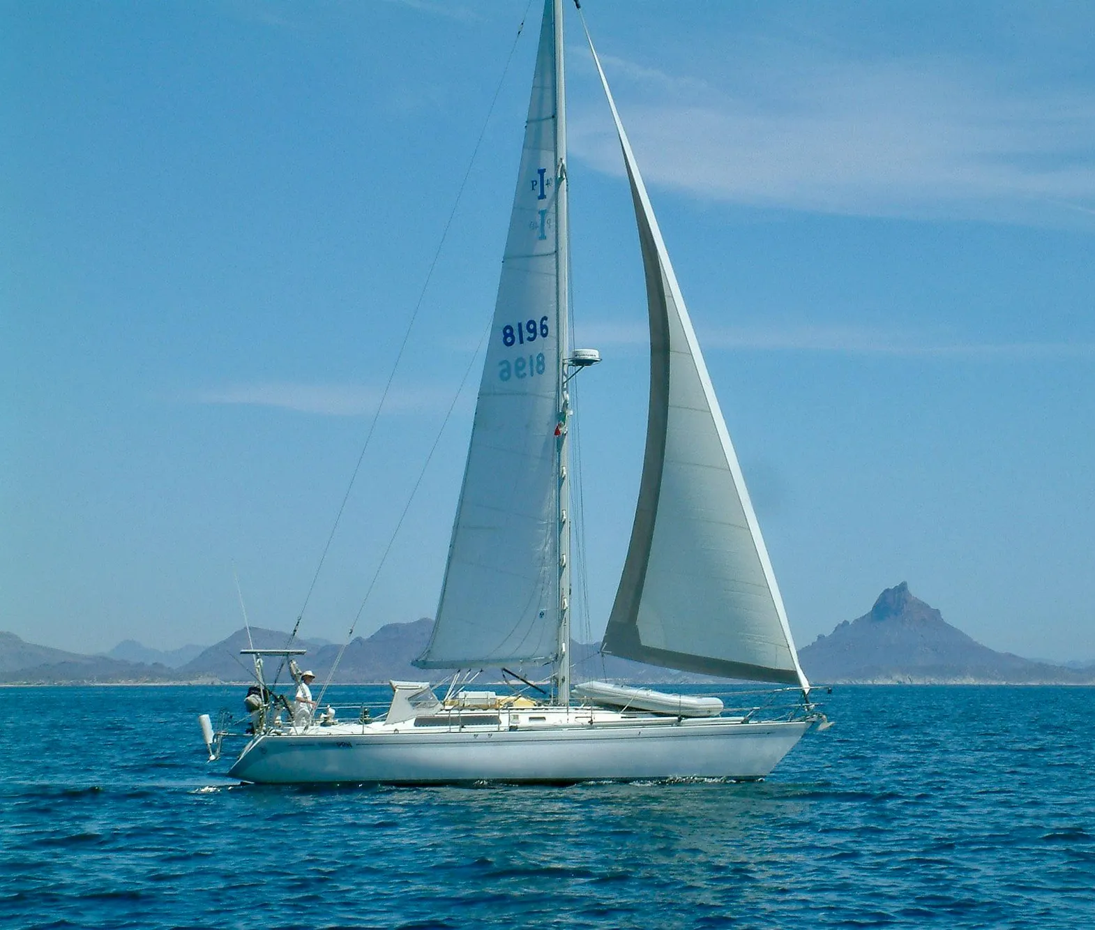 1979 Islander IP Peterson 40 sailboat cruising on open water with distant mountains.