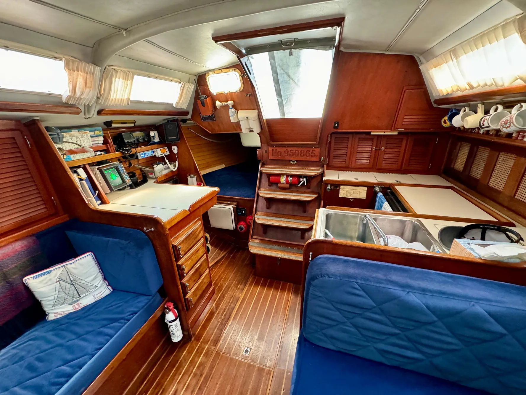 Interior of 1979 Islander IP Peterson 40 sailboat with wood finish and blue seating.