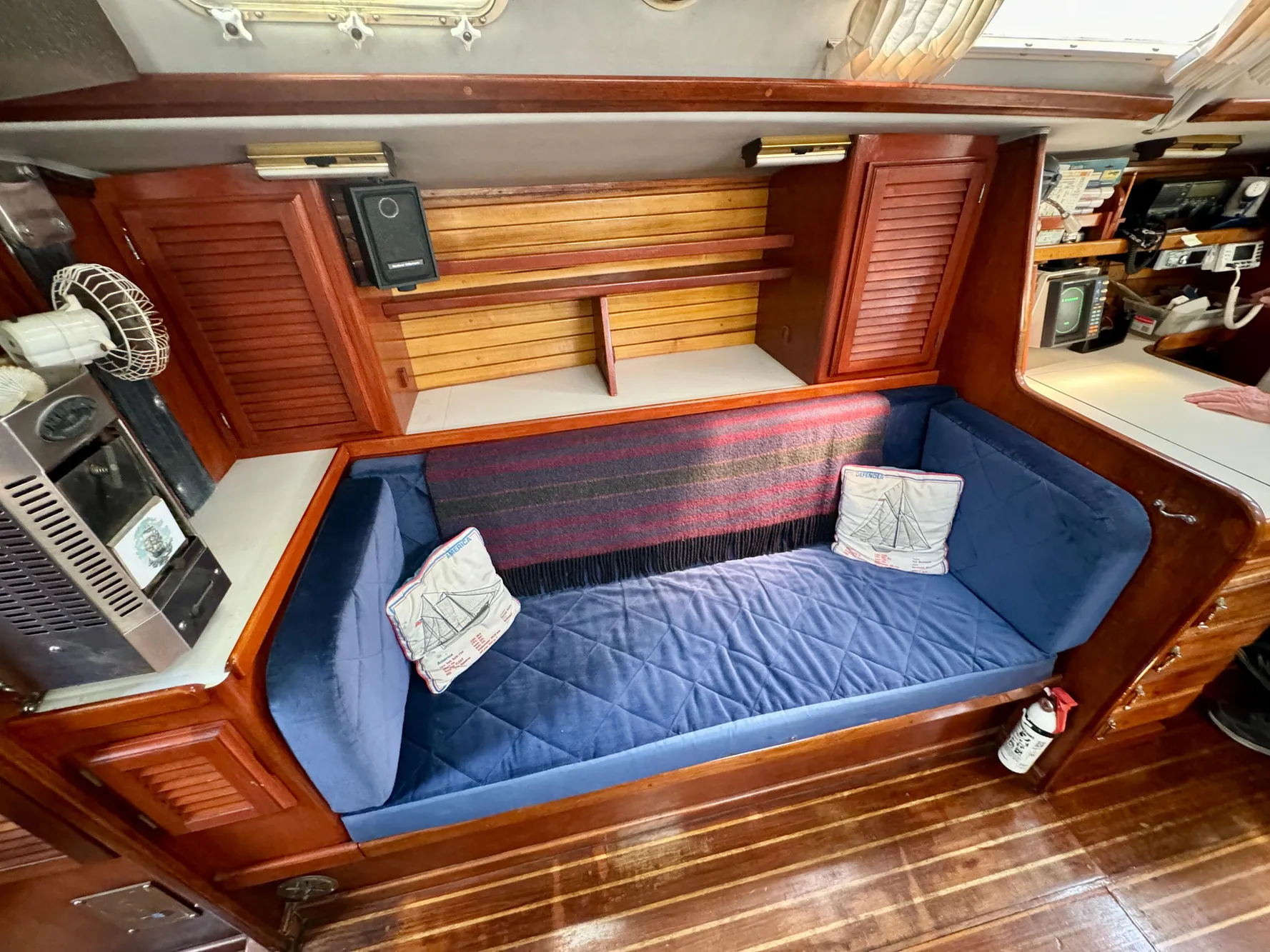 Interior of 1979 Islander IP Peterson 40 sailboat with blue cushioned seating and wooden cabinetry.