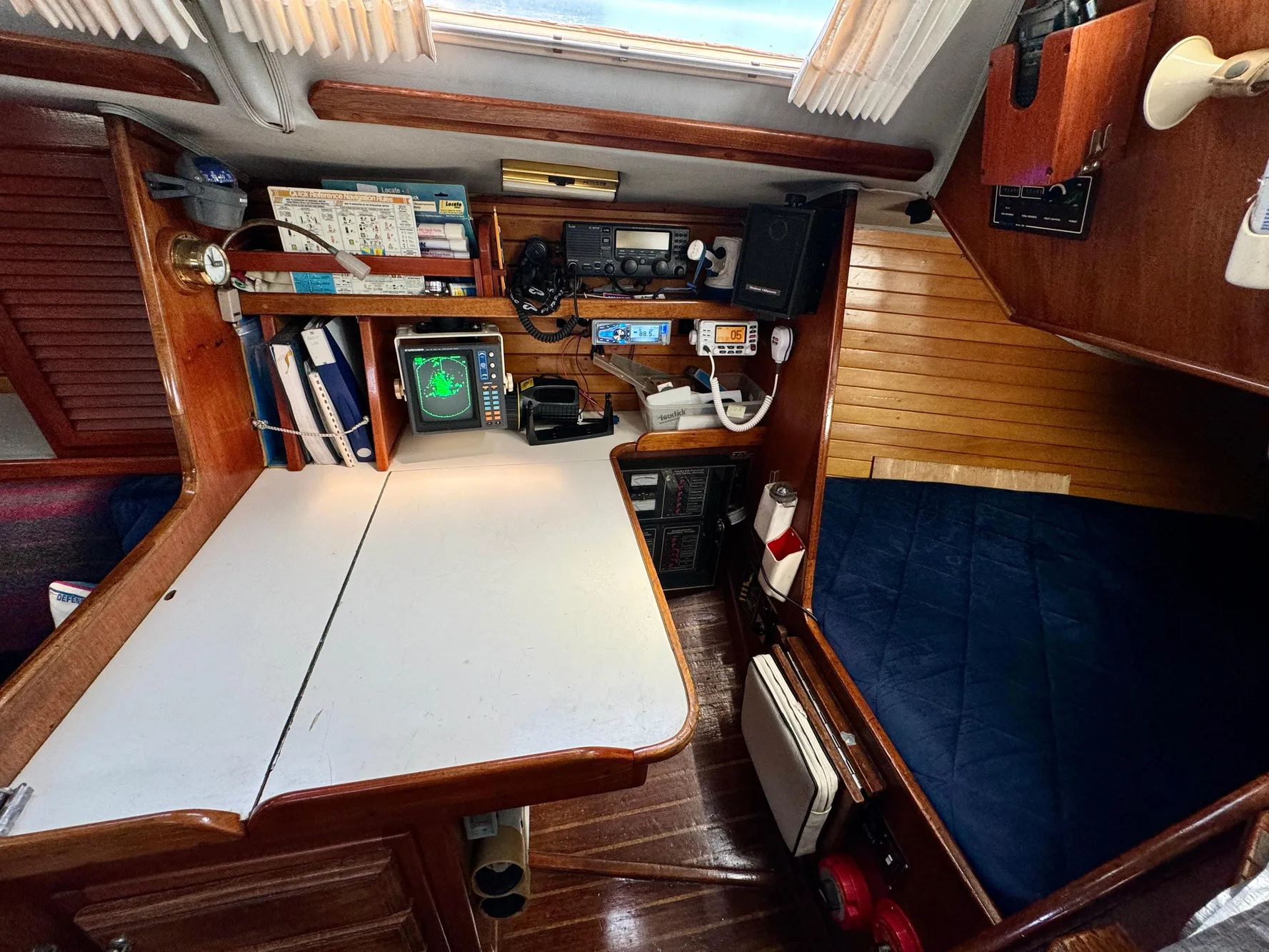 Navigation station inside 1979 Islander IP Peterson 40 sailboat with equipment and cozy cabin.