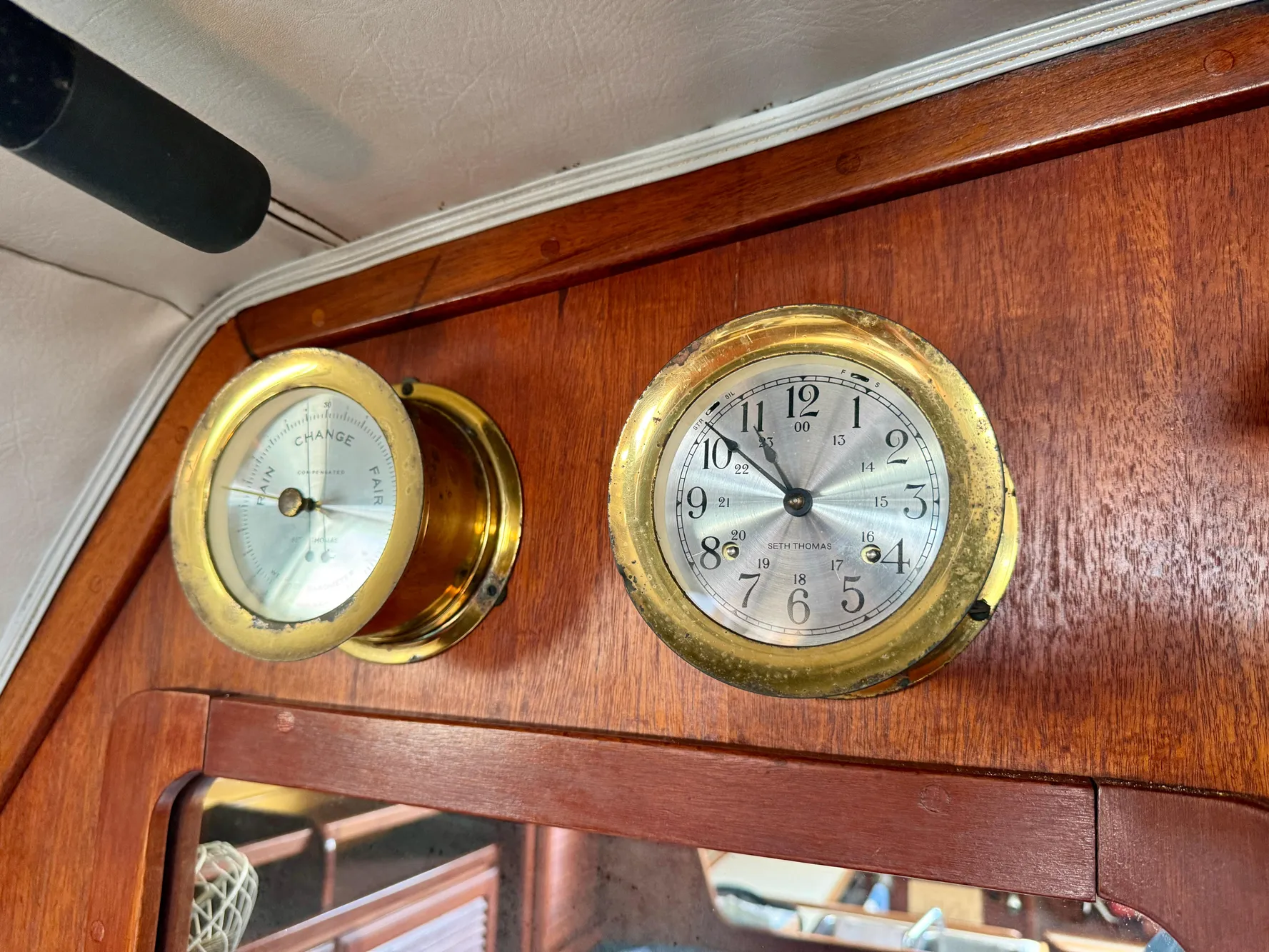 Brass clock and barometer on 1979 Islander IP Peterson 40 yacht's wooden interior.