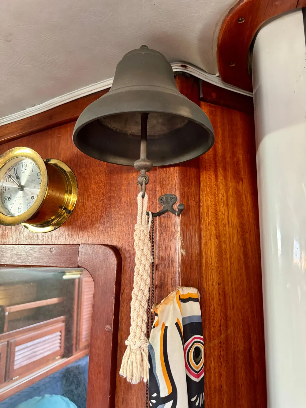 Vintage ship bell on 1979 Islander IP Peterson 40, with nautical decor and clock.