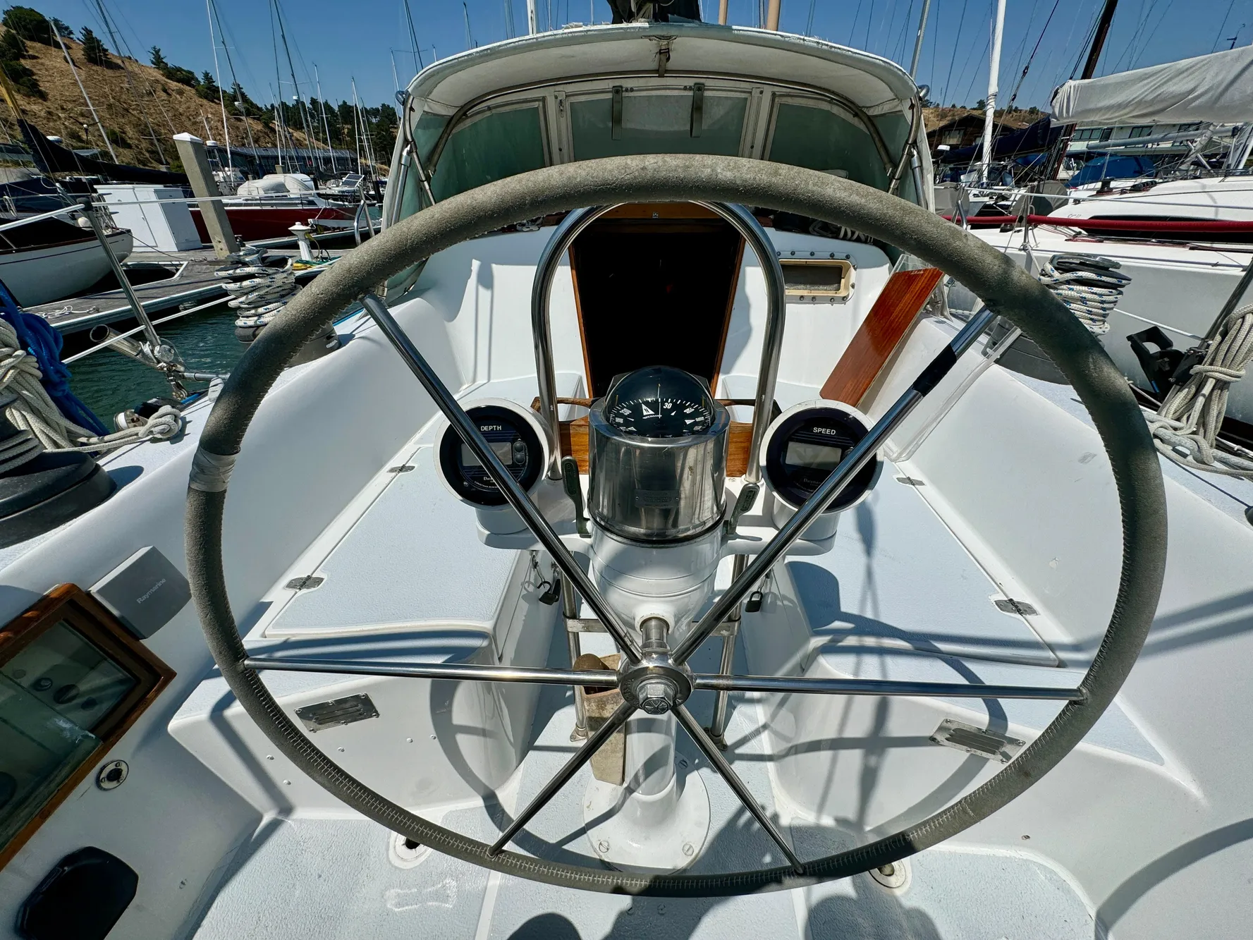 Steering wheel of 1979 Islander IP Peterson 40 sailboat in marina setting.