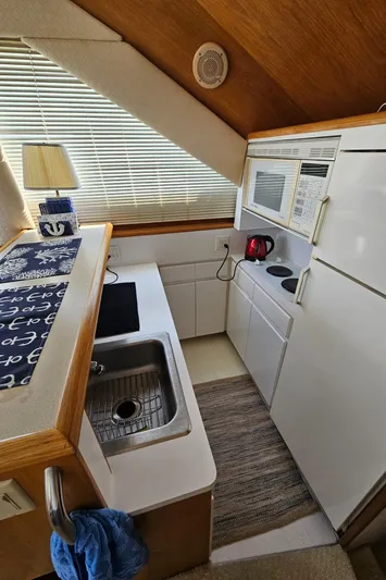  Yacht Photos Pics Compact kitchen in a 1995 Hatteras 39 Sportfish boat with sink, stove, and microwave.
