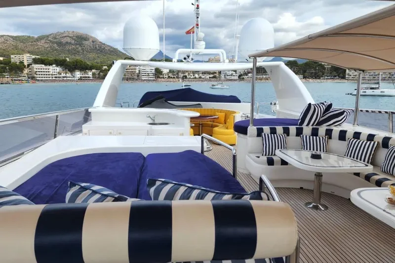  Yacht Photos Pics Luxurious Horizon 105 yacht deck with striped seating, ocean view, and coastal backdrop.