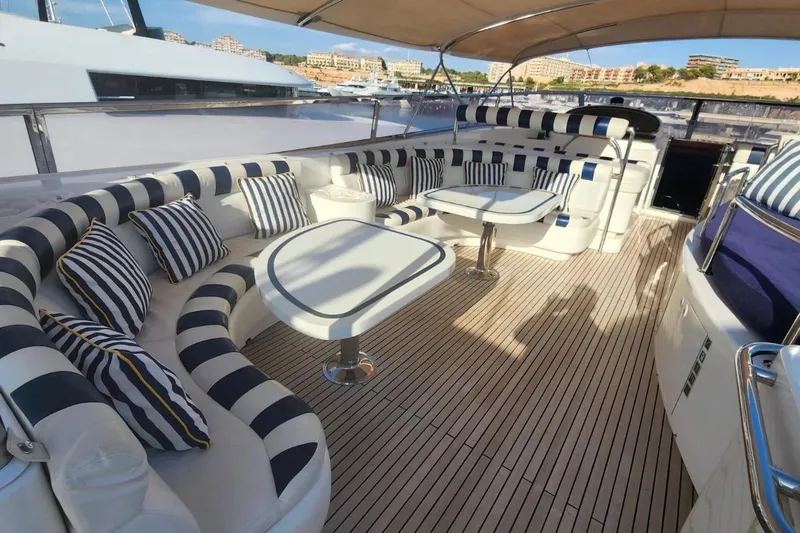  Yacht Photos Pics Luxurious 2002 Horizon 105 yacht deck with striped seating and tables, docked in a marina.