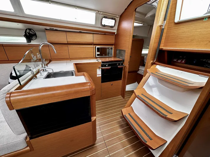  Yacht Photos Pics Interior of 2011 Jeanneau Sun Odyssey 409 yacht, featuring modern kitchen and wooden stairs.