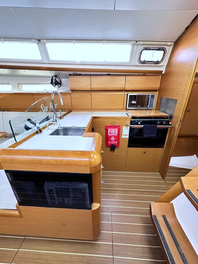  Yacht Photos Pics Interior of 2011 Jeanneau Sun Odyssey 409 yacht, featuring modern kitchen and wooden cabinetry.
