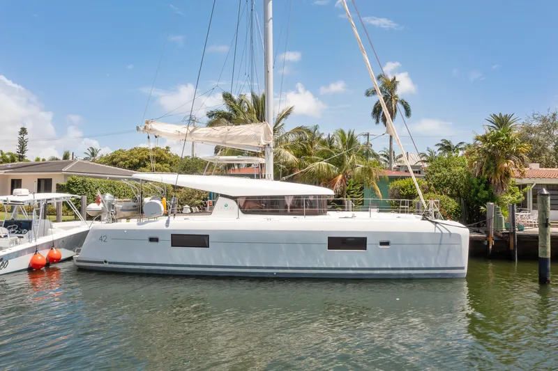 Curvy Mermaid Yacht Photos Pics 2017 Lagoon 42 Owners Version catamaran docked by tropical waterfront homes.