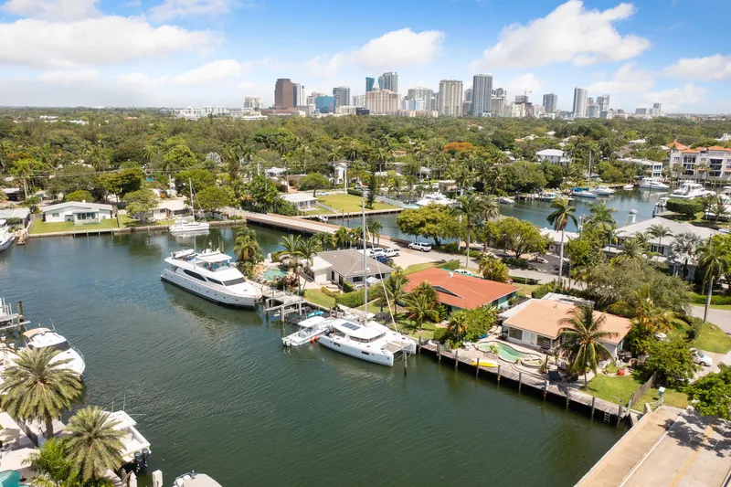 Curvy Mermaid Yacht Photos Pics Aerial view of a marina with a 2017 Lagoon 42 catamaran, city skyline in background.
