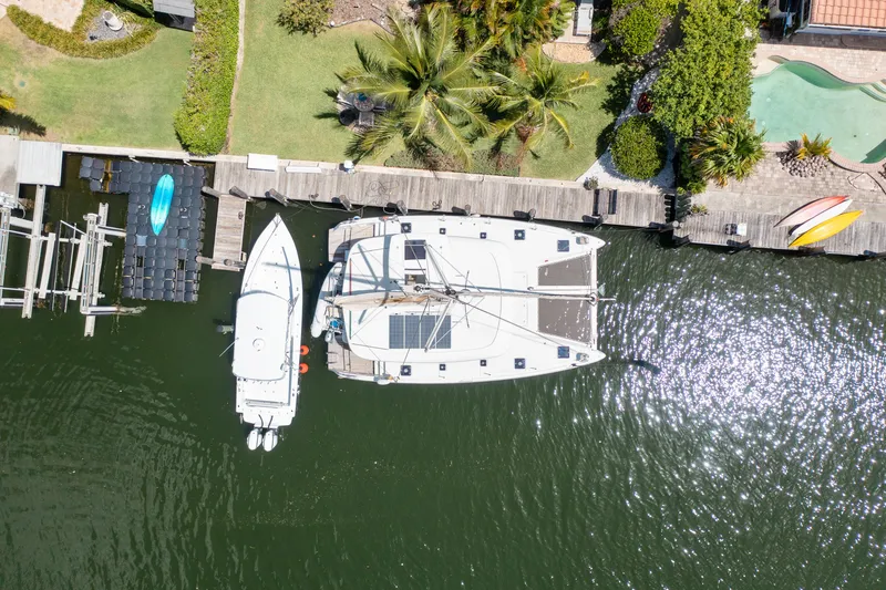 Curvy Mermaid Yacht Photos Pics Aerial view of a 2017 Lagoon 42 catamaran docked beside a motorboat and kayaks.